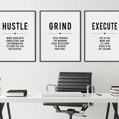 two black and white posters on the wall above a desk with a chair, vase and books