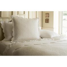 a white bed with two pillows on top of it