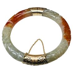 This is a 14K gold carved jadeite jade hinged bangle/bracelet. It depicts a light green and red brown color jadeite jade bracelet carved with some leaves. The bracelet is enhanced by a 14K gold hinge and clasp adorned with filigree scrolls. The bracelet has a cylindrical box closure with safety chain. It is hallmarked HK and 14K. Measurement of the wrist- 4.5 inches. Jade Bracelet Bangles, Red Jade Bracelet, Jadeite Jewelry, Jade Bangle, Jade Bracelet, Green And Red, Hinged Bangle, Red Brown, Bangle Bracelet