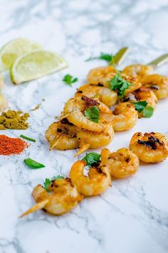 the shrimp skewers are ready to be served on the table with lime wedges