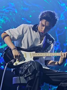 a young man playing an electric guitar on stage