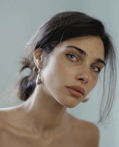 a close up of a woman wearing earrings and looking off to the side with her hand on her hip