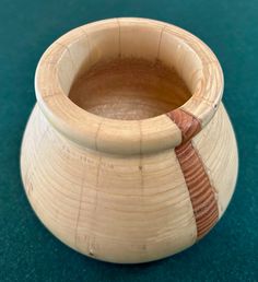 a wooden bowl with a striped handle on a green tableclothed surface and a blue background