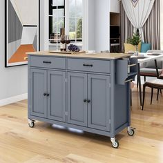 a gray kitchen island with wooden top on wheels in a living room next to a dining room table