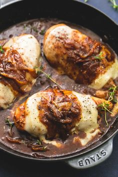 three pieces of meat in a pan with sauce and herbs