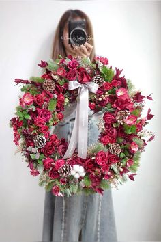 a woman taking a photo of a wreath with a camera in front of her face