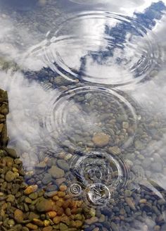 some rocks and water with clouds in the background