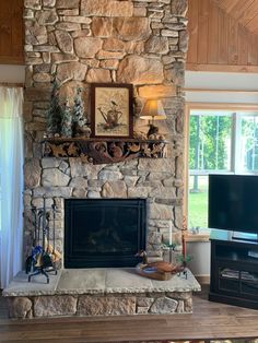 a living room with a stone fireplace and flat screen tv mounted on the wall above it