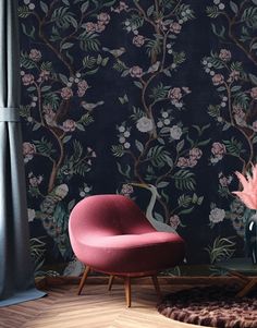 a pink chair sitting in front of a black wall with flowers and birds on it