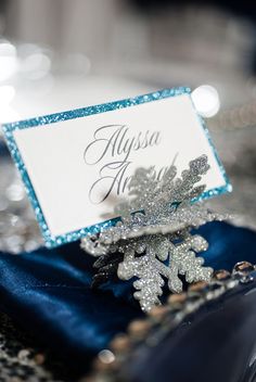 a place card holder with snowflakes on it is sitting on a blue cloth