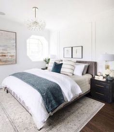 a bedroom with white walls and wood flooring has a large bed in the center