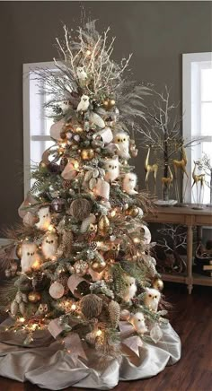 a white christmas tree with ornaments and lights in the shape of animals on it's branches