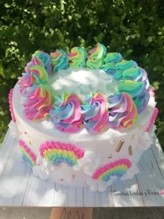 a cake with rainbow frosting and sprinkles sitting on top of a wooden table