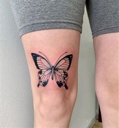 a woman's leg with a butterfly tattoo on it, which is black and white