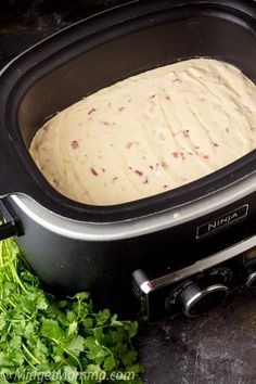 a close up of a bread in a crock pot with parsley on the side