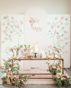 a table topped with lots of flowers and cake next to a wall covered in florals