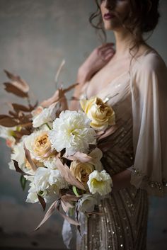 a woman holding a bouquet of white and yellow flowers in her hands, wearing an evening gown