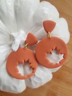 an orange pair of earrings on top of a white flower