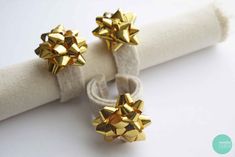 two gold bowknots sitting on top of a white napkin