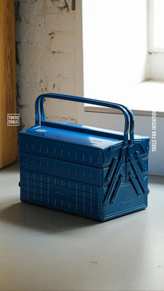 a blue plastic box sitting on top of a table next to a window with the lid open