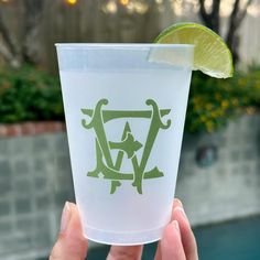 a person holding up a plastic cup with a lime wedge in it