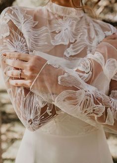 a close up of a person wearing a wedding dress and holding her hands together in front of the camera