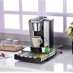 a coffee maker sitting on top of a counter next to a vase with flowers in it