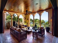 an outdoor living area with couches, tables and ceiling fan on the balcony overlooking the ocean