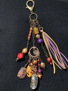 a close up of a key chain on a black surface with beads and charms hanging from it