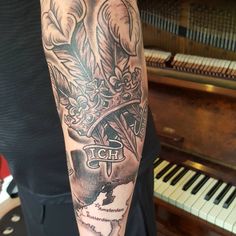 a person with a tattoo on their arm next to a piano and an old - fashioned keyboard