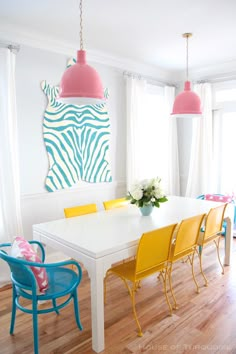 a white table with yellow chairs and pink lamps