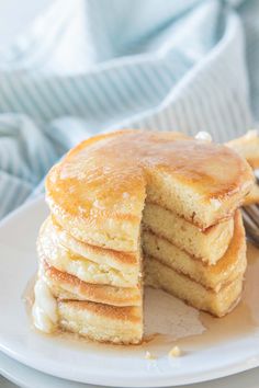 a stack of pancakes sitting on top of a white plate next to a knife and fork