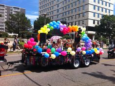 a parade float with balloons and people riding in the back