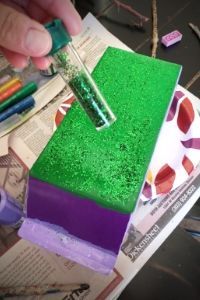 a person is decorating a cake with green frosting and crayons on it