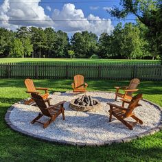 a fire pit with chairs around it in the grass