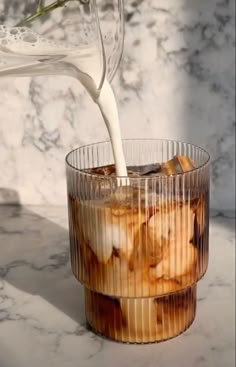 a drink being poured into a glass with ice