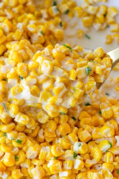 a spoon is full of corn on the cob with sour cream and parsley