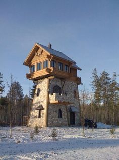 a large stone tower with a clock on it's side in the middle of snow