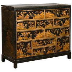 an ornate black and gold painted chest of drawers