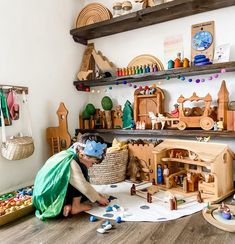 a child playing with wooden toys on the floor in front of shelves filled with dolls