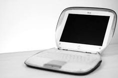 an open laptop computer sitting on top of a wooden table next to a white wall