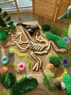 a rug made to look like a lizard on the ground with plants and rocks around it