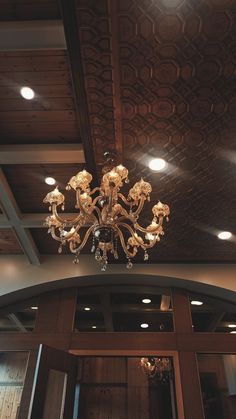 a chandelier hanging from the ceiling in a room with wood paneled walls