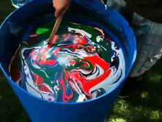 a blue bucket filled with colorful liquid on top of grass