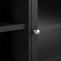 the door is open to reveal a black cabinet with silver handles and knobs on it