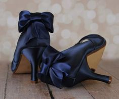 a pair of black high heeled shoes with a bow