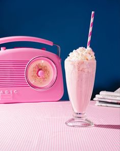 a pink ice cream sundae next to an old fashioned radio on a table with blue background