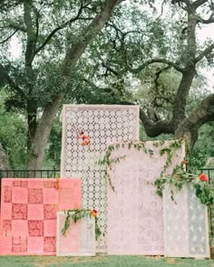 an outdoor ceremony area with pink and white quilts, greenery, and flowers