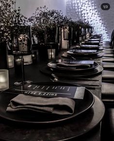 the table is set with black plates and candles