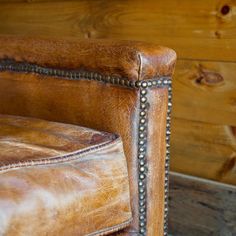 a brown leather chair with studded nailing on the arm and footrests